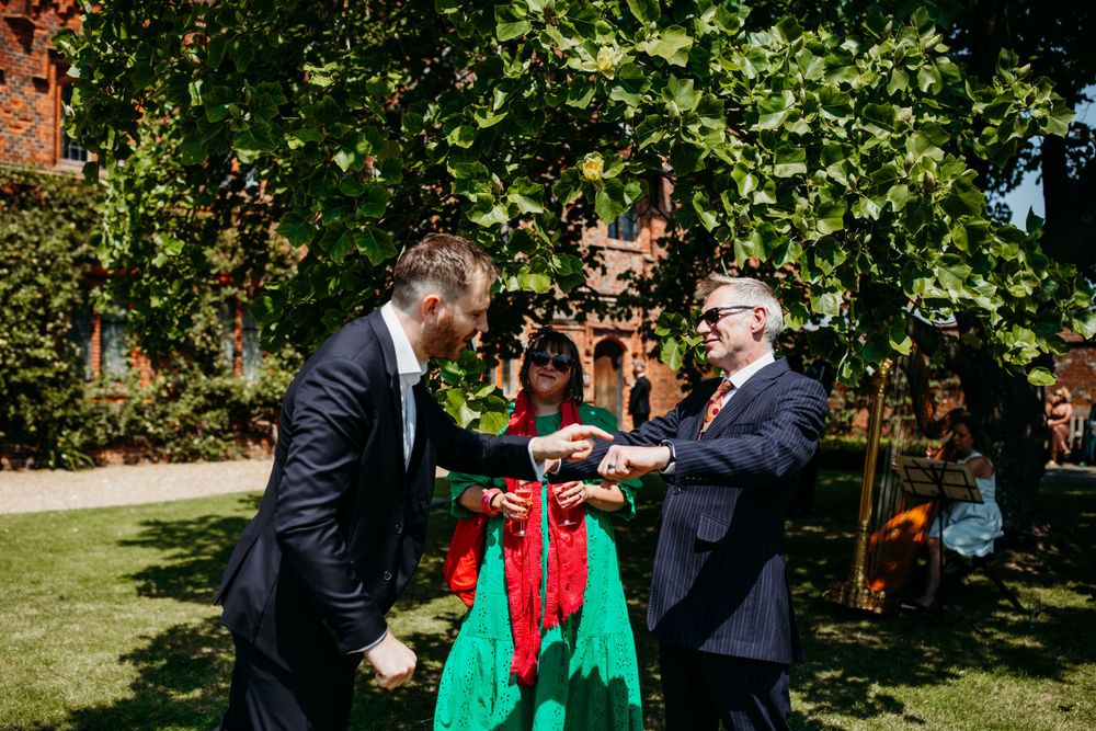 Wedding celebration in a garden setting with blooming vines and red brick walls.