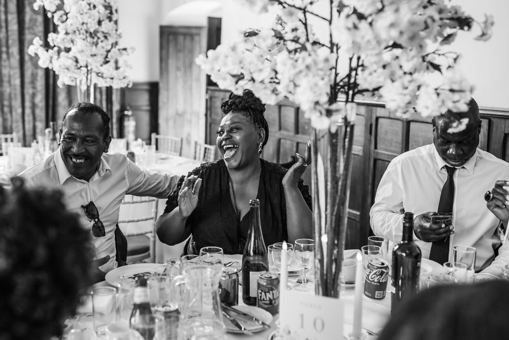 Wedding guests share laughter during a reception dinner.