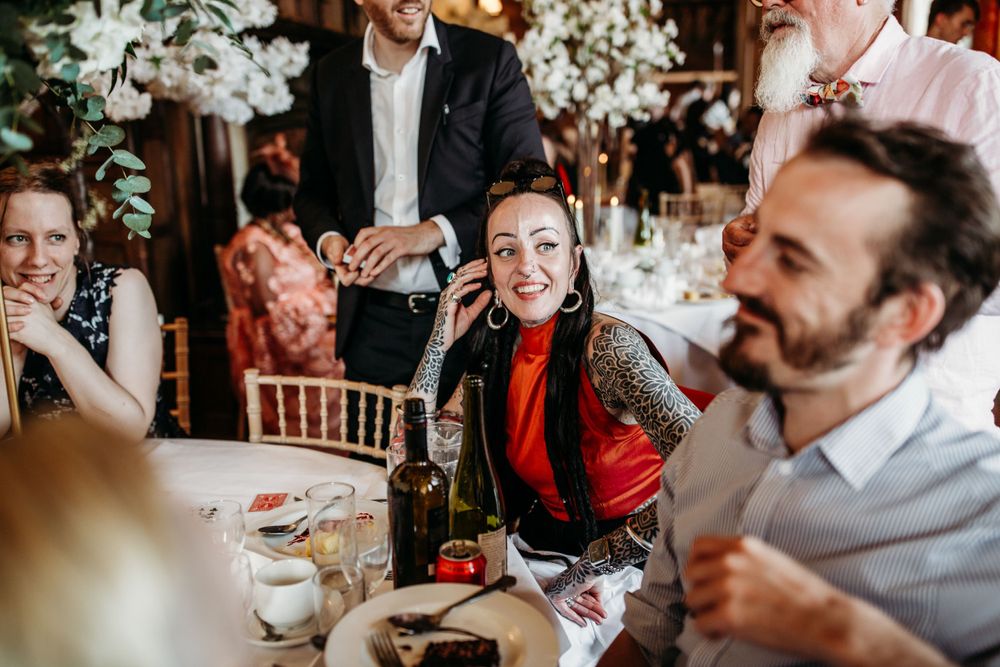 Reception guests enjoying conversation at a table decorated with white floral arrangements.