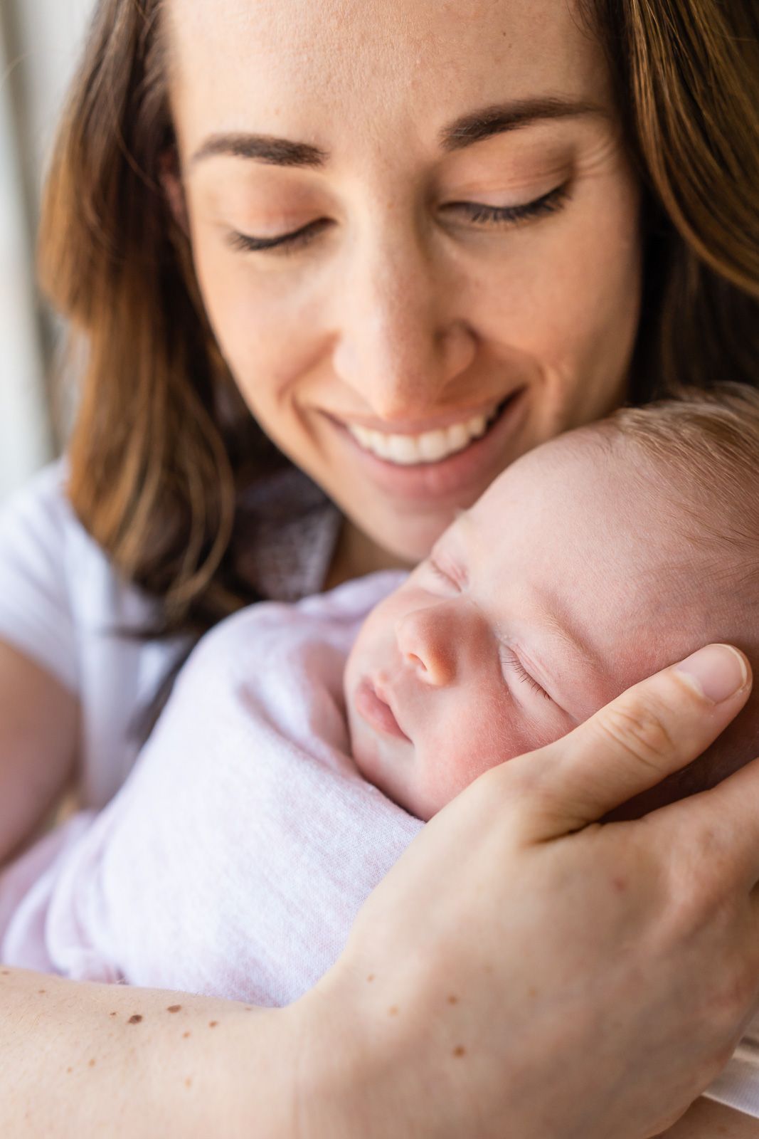 Detail photo of newborn's eyelashes while mom smiles on.