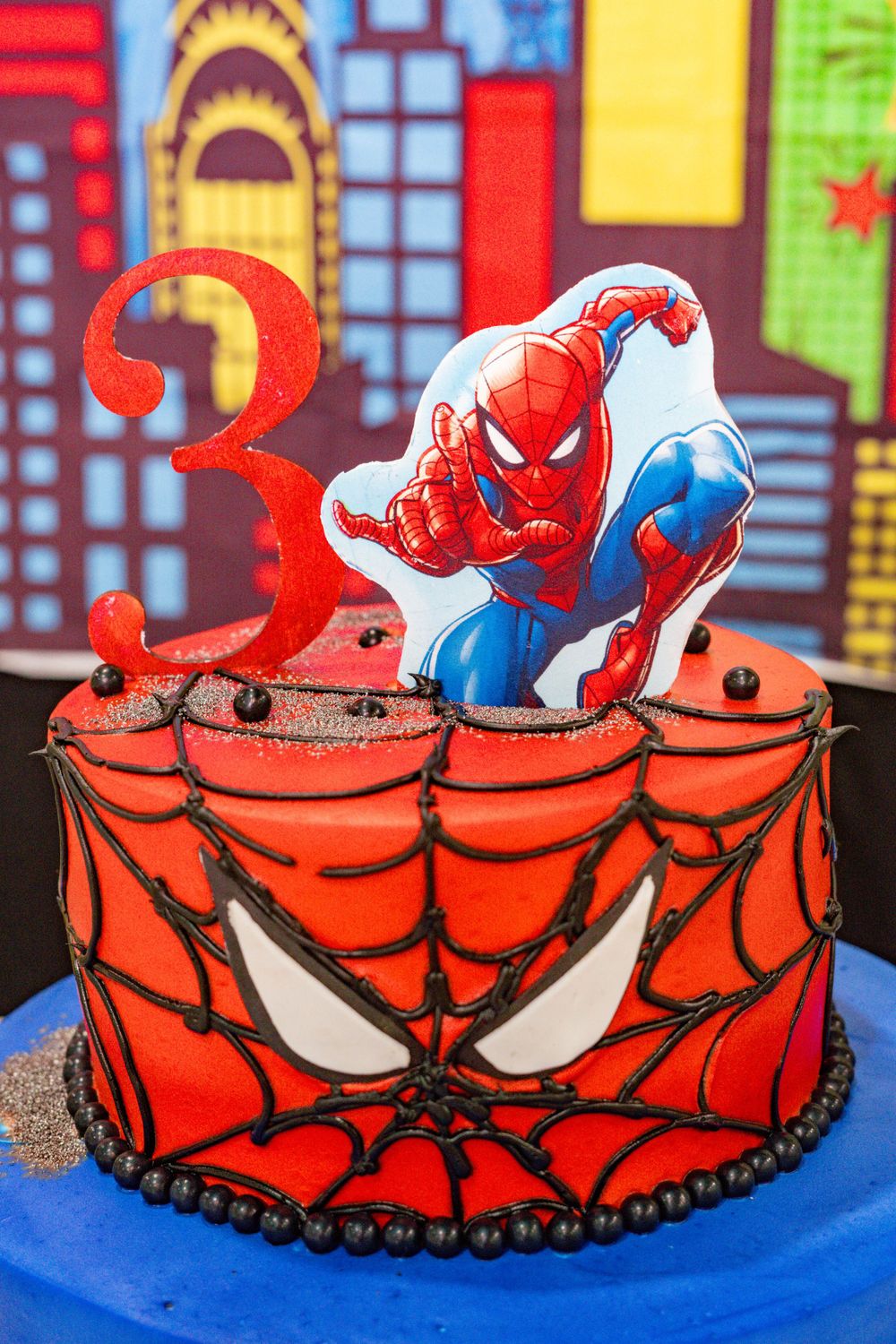 Spiderman-themed red birthday cake with number 3 candle topper.