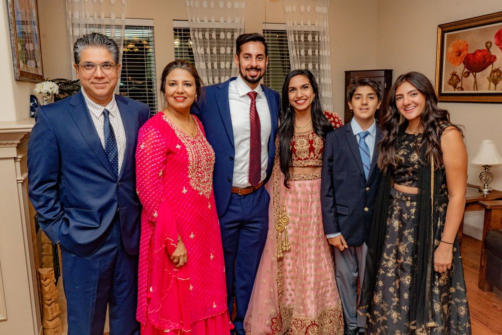 Family of six posing together in formal attire at an Indian wedding celebration.