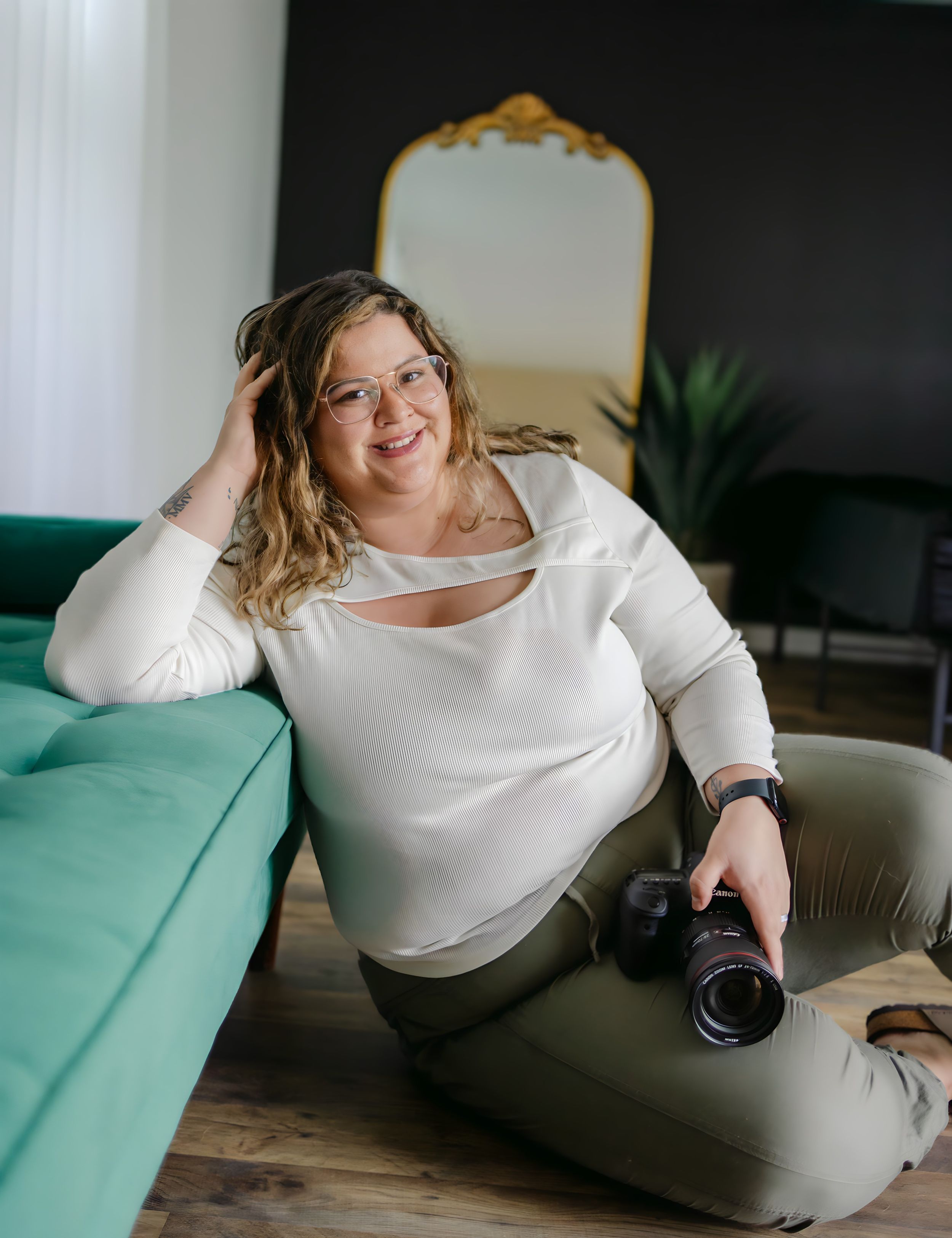 Lifestyle portraits on teal couch wearing white sweater in modern interior setting.