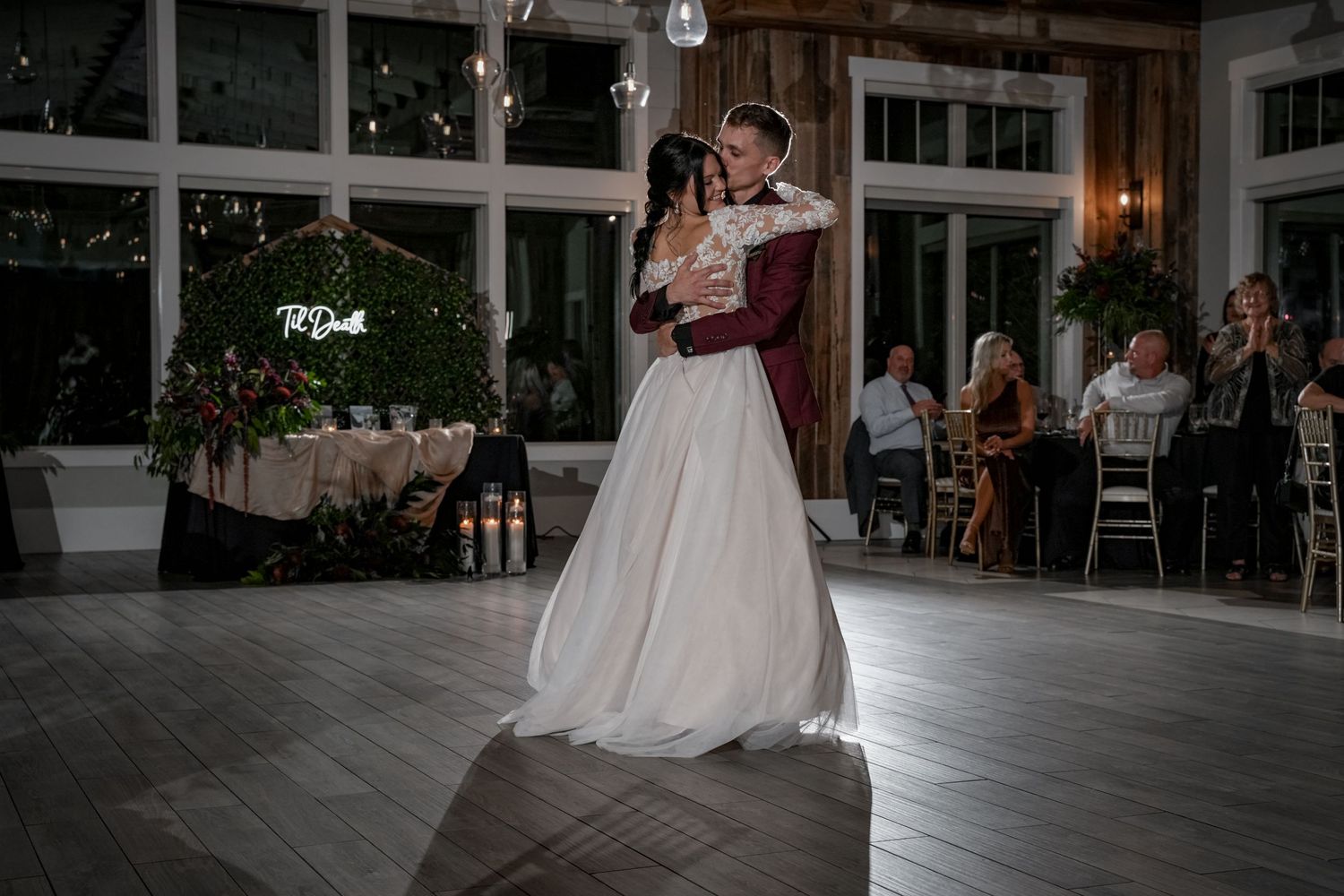 First dance in elegant reception venue with guests watching from decorated tables.