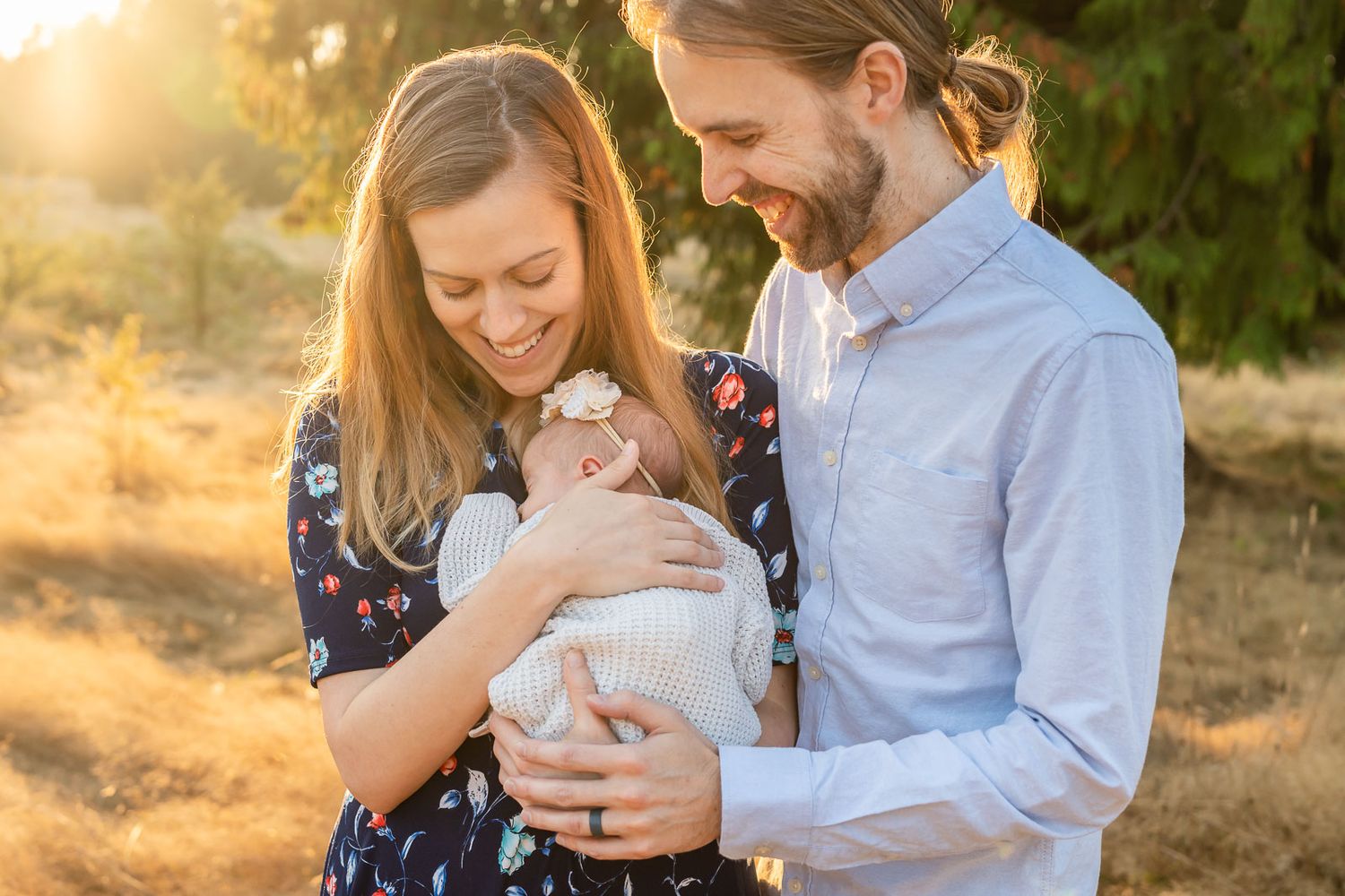 Parents snuggling with newborn daughter at sunset in Woodinville.
