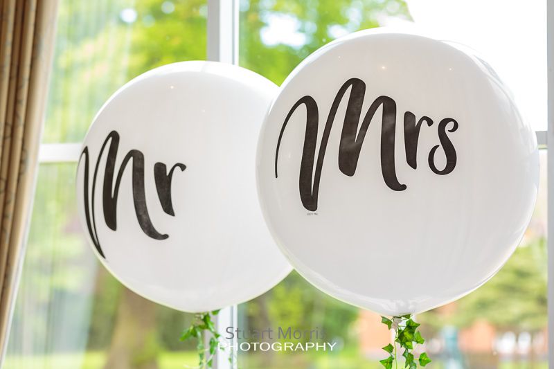 mr and mrs large white balloons floating above the top table at craxton wood
