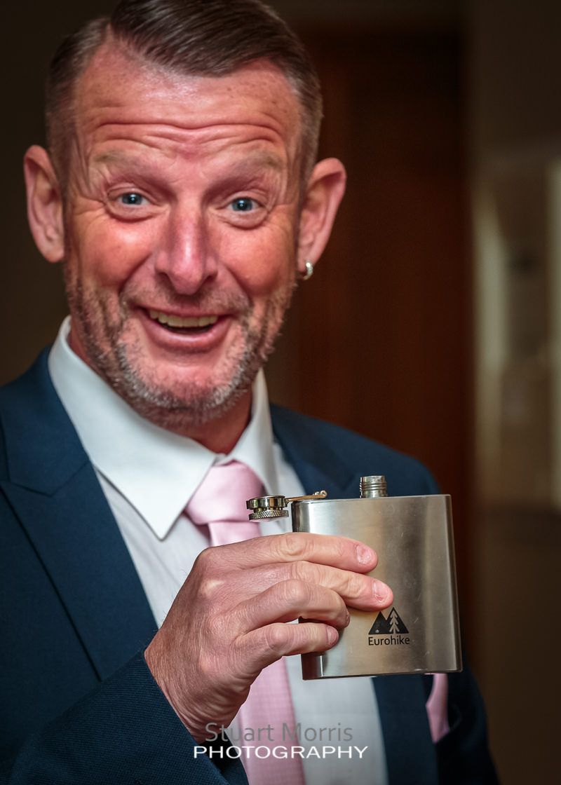 wedding guest showing off his hip flask before the ceremony