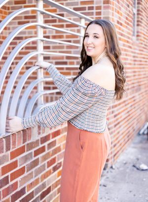 senior girl outside by brick wall with cool railing