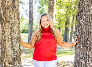 senior girl in red by trees outside