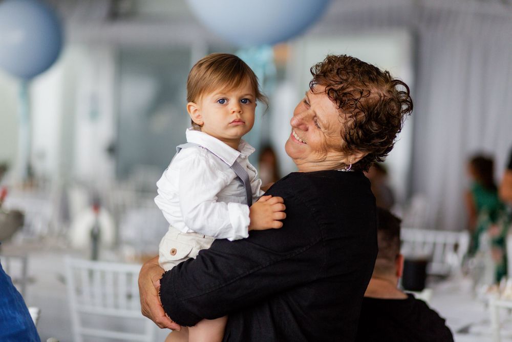 Sweet embrace between child in formal white outfit and loved one at celebration.