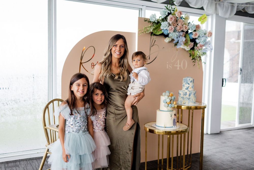 Celebration photo against beige backdrop with floral decorations and gold cake stands.