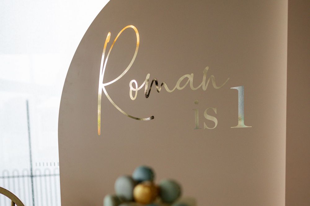 Gold lettering reading 'Roman is 1' displayed on a beige wall backdrop.