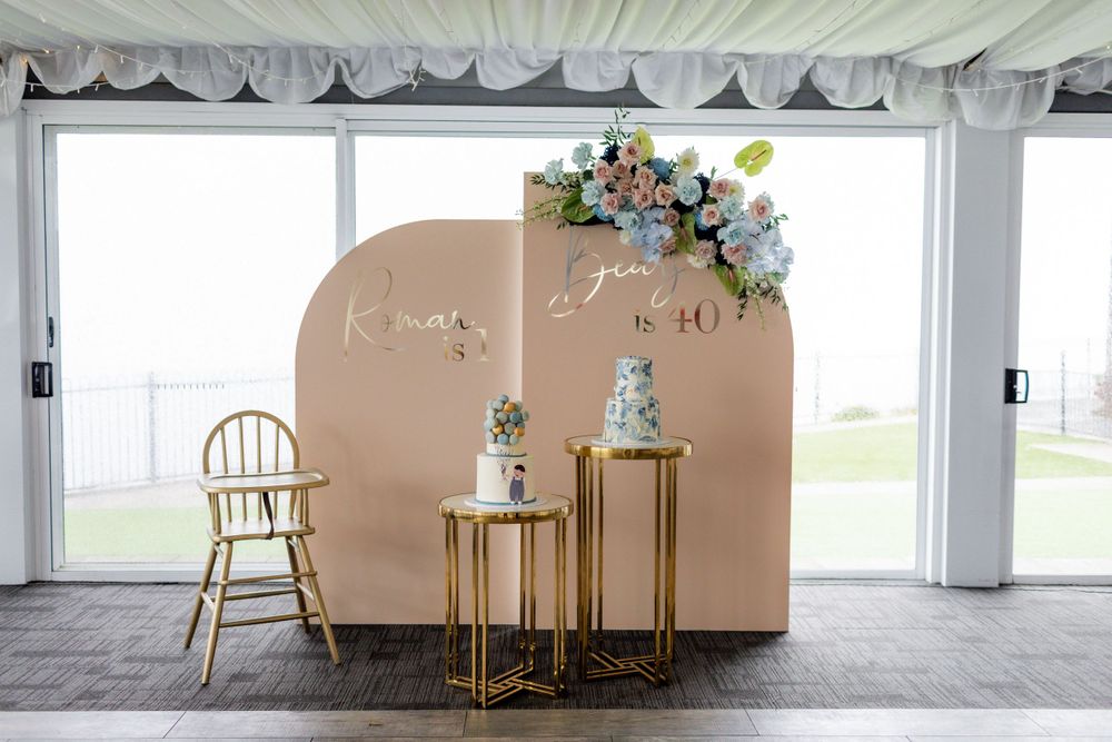 Event setup with beige backdrop, gold furnishings, and blue floral arrangements in an elegant venue.