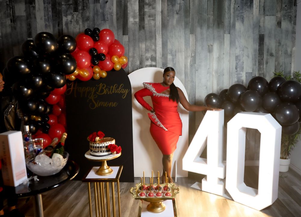 Birthday setup with red dress, large 40 sign, and black and red balloon decorations.