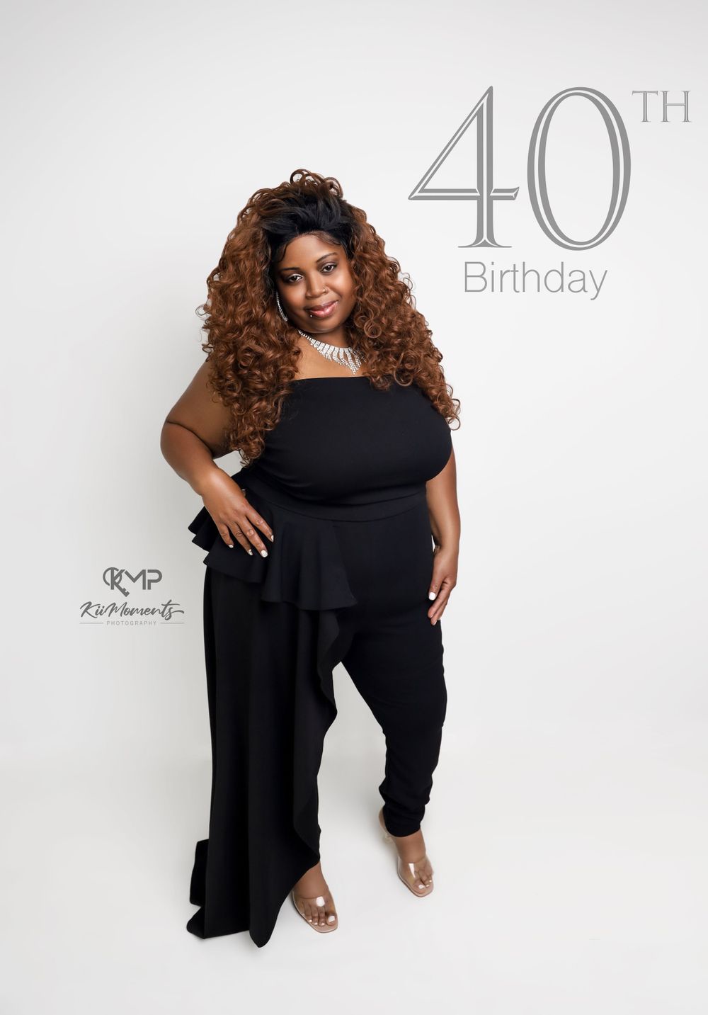 40th birthday portrait featuring black outfit and curled hair against white background.