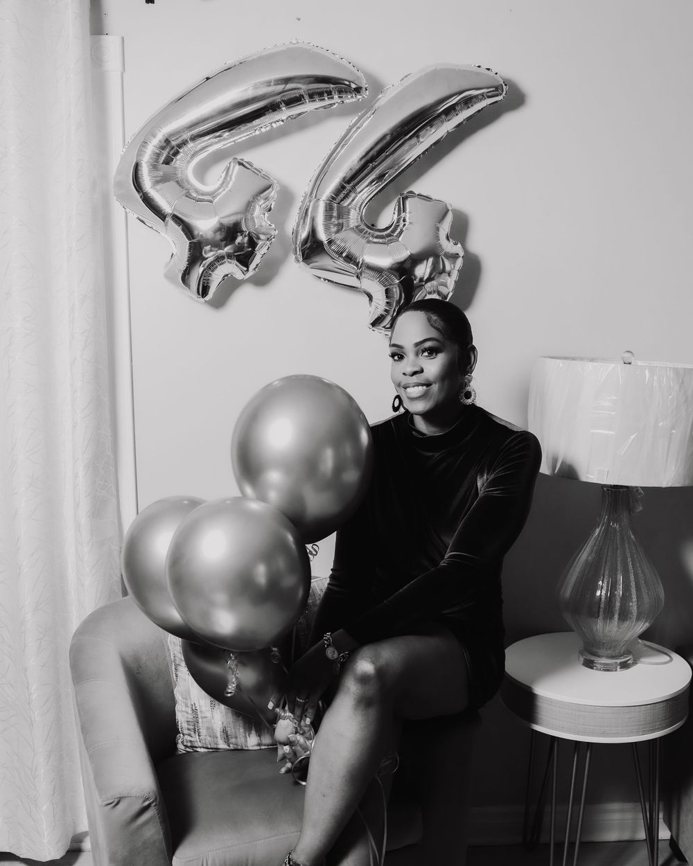 Black and white portrait with silver number 44 balloons and elegant pose.