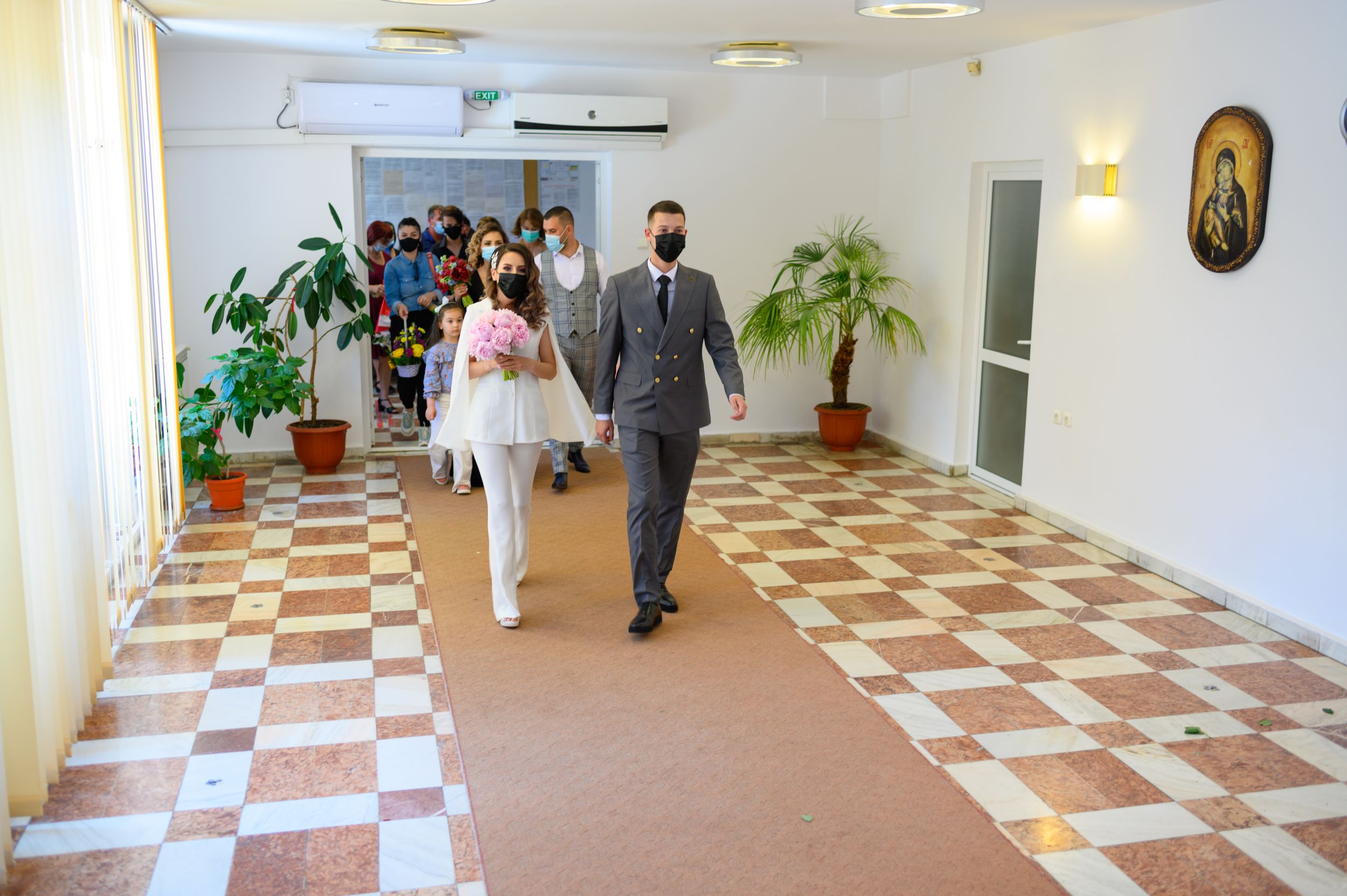 Long hallway with checkered floor and white walls during a wedding ceremony.