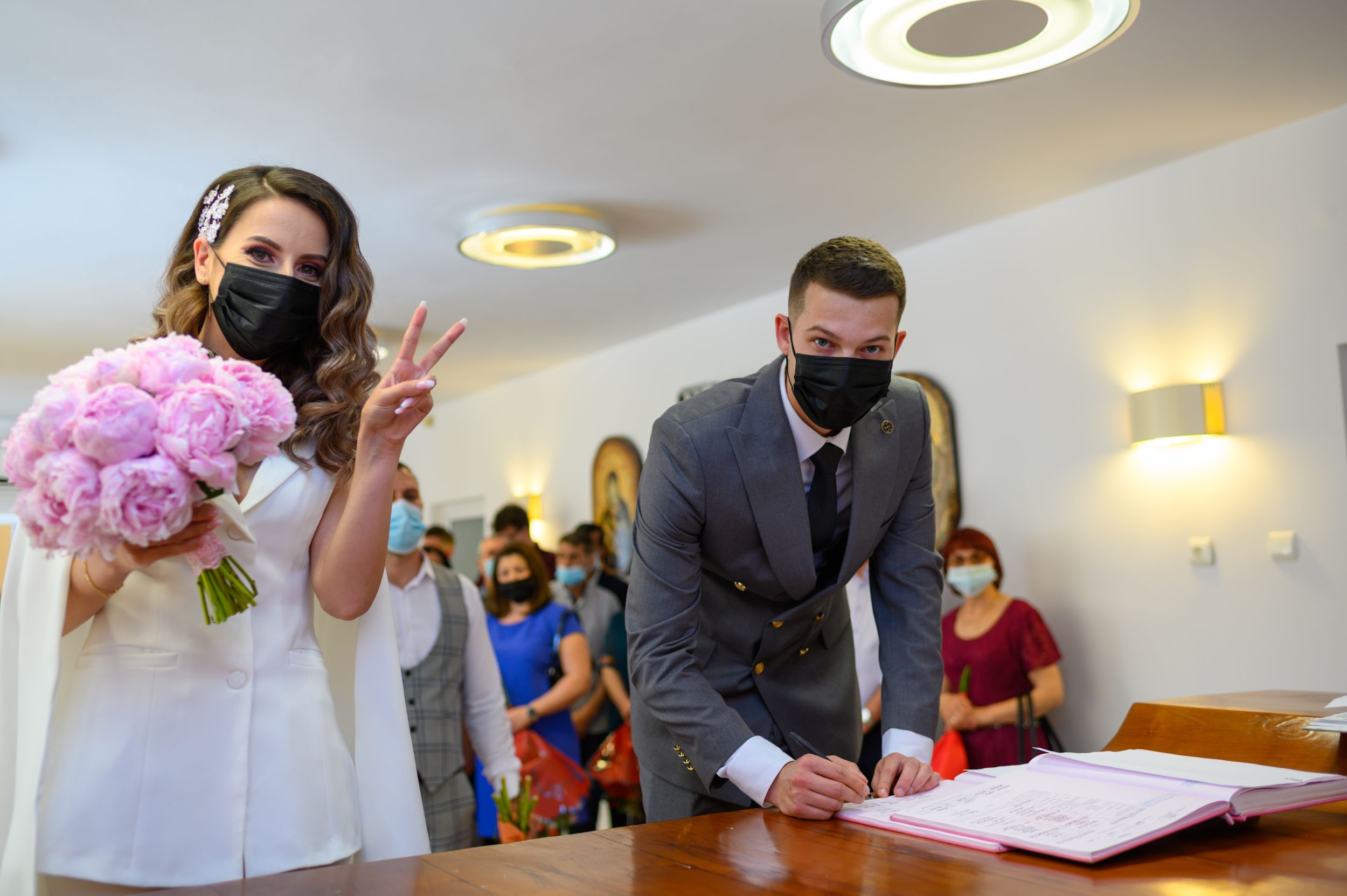 Wedding signing ceremony in progress with attendees wearing protective masks.