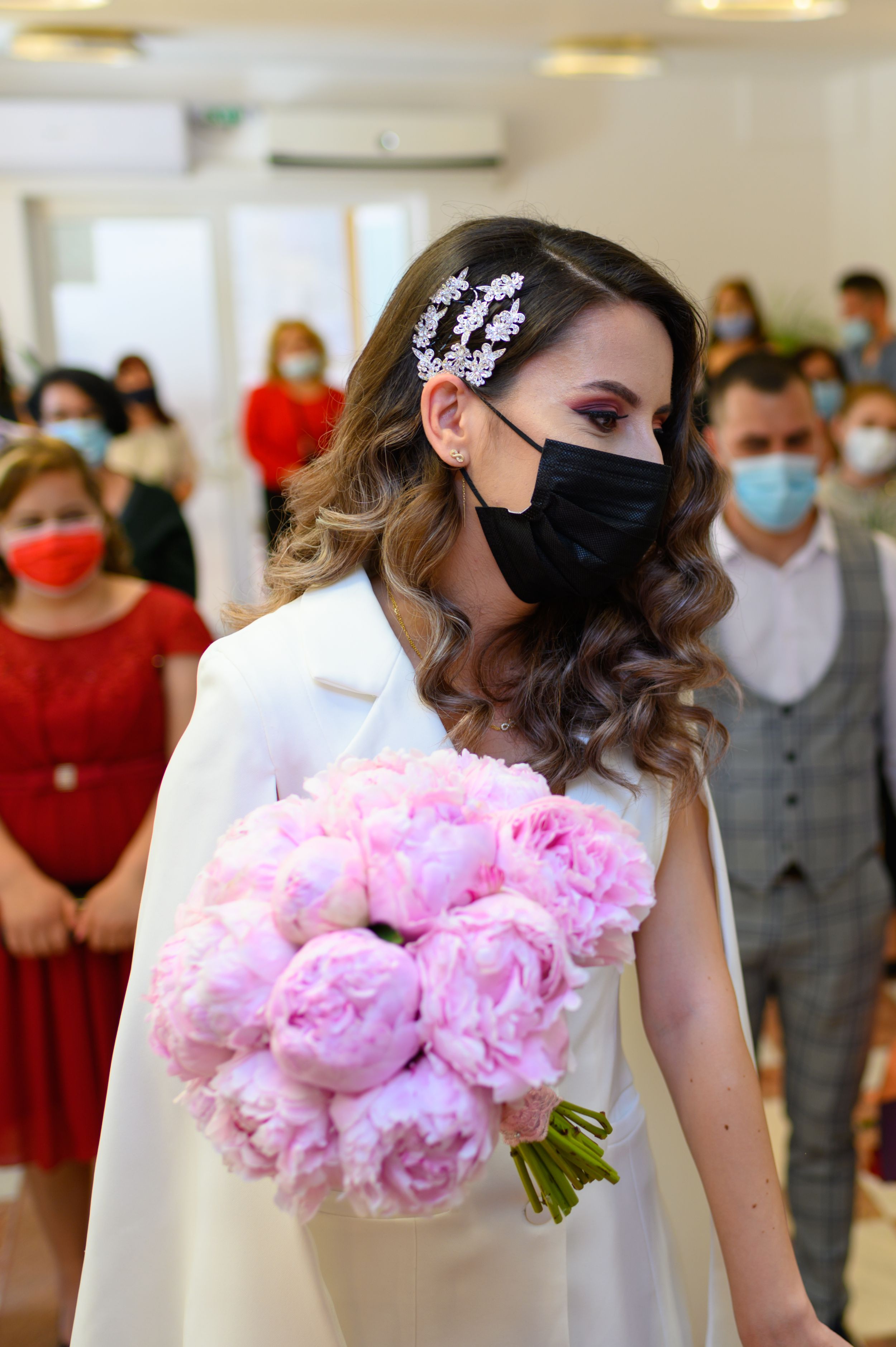 Bride holding a stunning bouquet of pink peonies while wearing a protective mask.