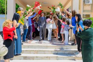 Wedding guests forming an archway with flowers and celebrating on outdoor steps.