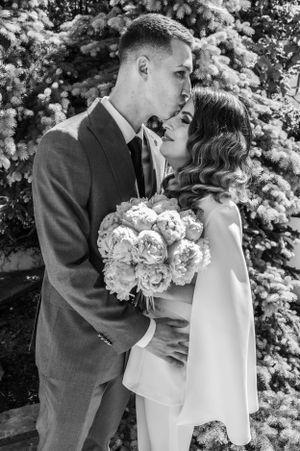 Black and white portrait of a romantic moment between newlyweds with a floral bouquet.