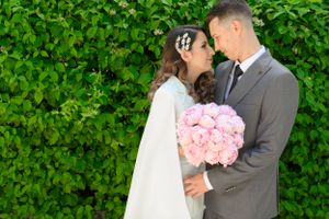 Romantic garden photoshoot with couple holding pink peony bouquet.