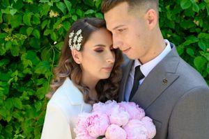 Intimate moment captured between couple with pink flowers and greenery backdrop.