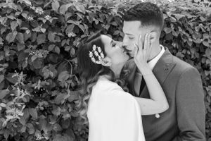 Black and white portrait of a couple sharing a romantic moment by a hedge.