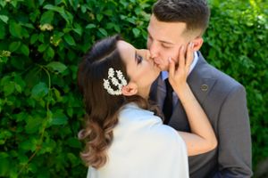 Romantic wedding portrait with couple embracing against garden backdrop.