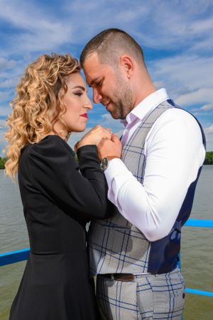 Romantic couple embracing on a boat dock with blue sky and water in the background.
