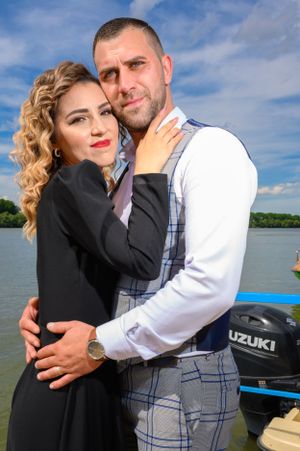Couple sharing intimate moments on a wooden dock with a Suzuki boat visible.