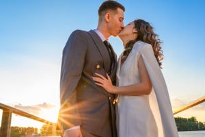Romantic sunset photoshoot with couple embracing against golden sky.