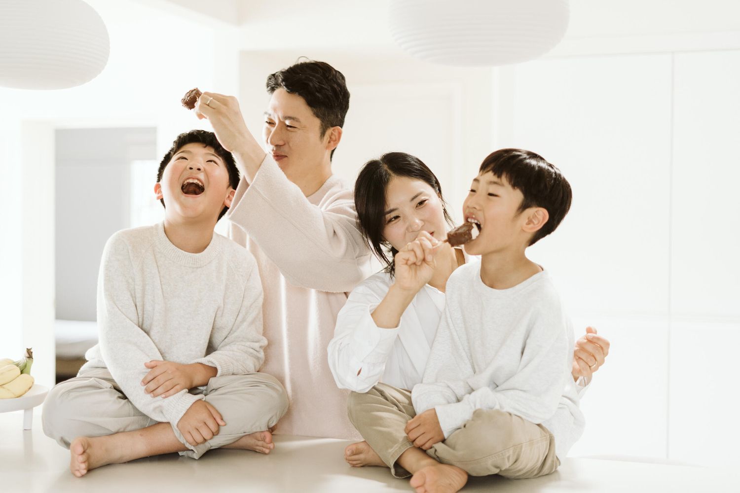In their North Melbourne home, parent and children feeding ice cream to each other while laughing and enjoying.