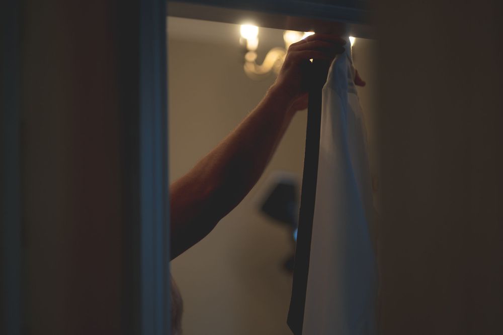 An arm reaches to adjust a dimly lit doorway or frame.