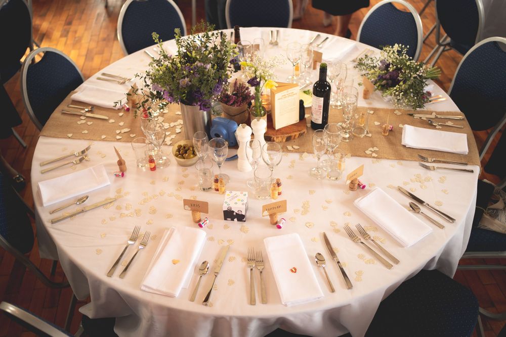 An elegant wedding reception table setting with floral centerpieces and place settings on a round table.