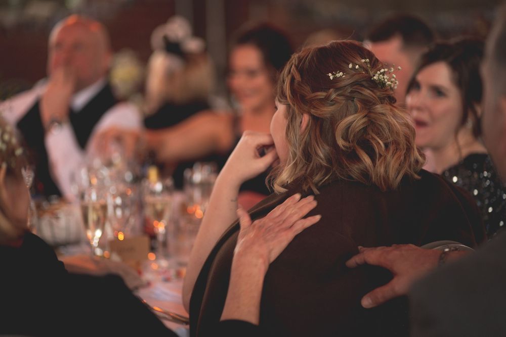 Wedding guests enjoying conversation at an evening reception with soft lighting.