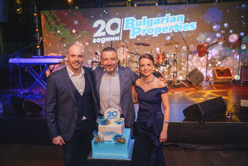 Event celebration with cake and presentation stage featuring 20th anniversary branding.