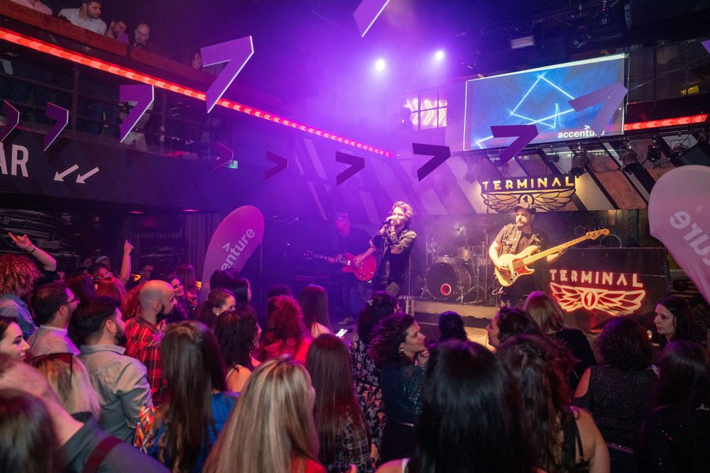 Concert crowd watches performer on stage with purple lighting at Terminal bar venue.