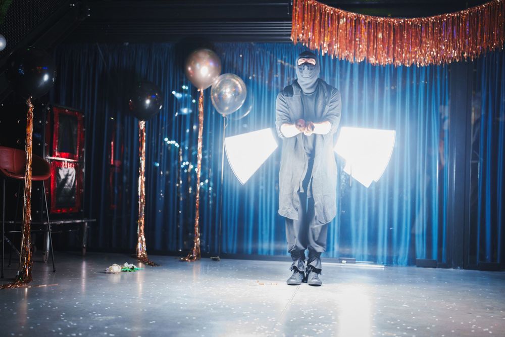 Performer in dark clothing creates theatrical lighting effect on stage with glowing props.