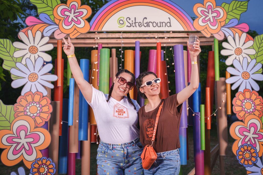 Two people pose playfully in front of a colorful floral photo backdrop with Silverboard branding.