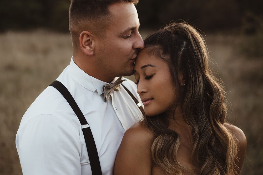 A tender moment between newlyweds captured in warm evening light with natural field backdrop.