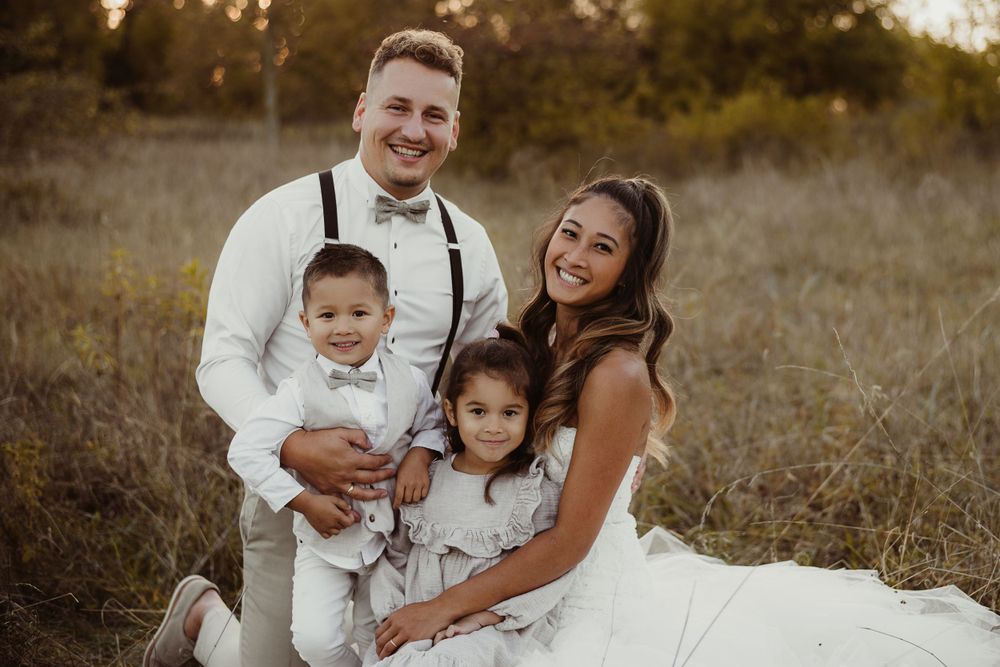 Happy family portrait in formal attire against golden sunset field backdrop.