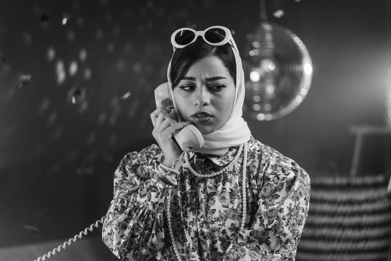 Black and white portrait of figure in headscarf using vintage telephone.
