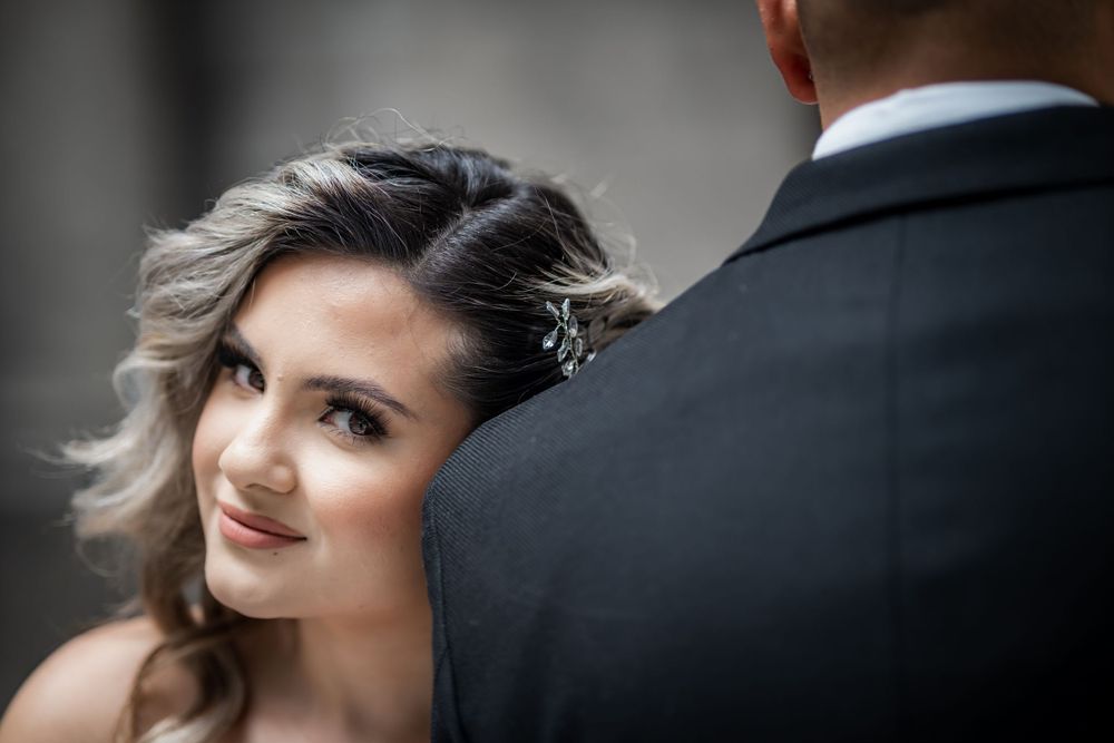 Bride gazes lovingly at groom in black suit during romantic wedding portrait session.