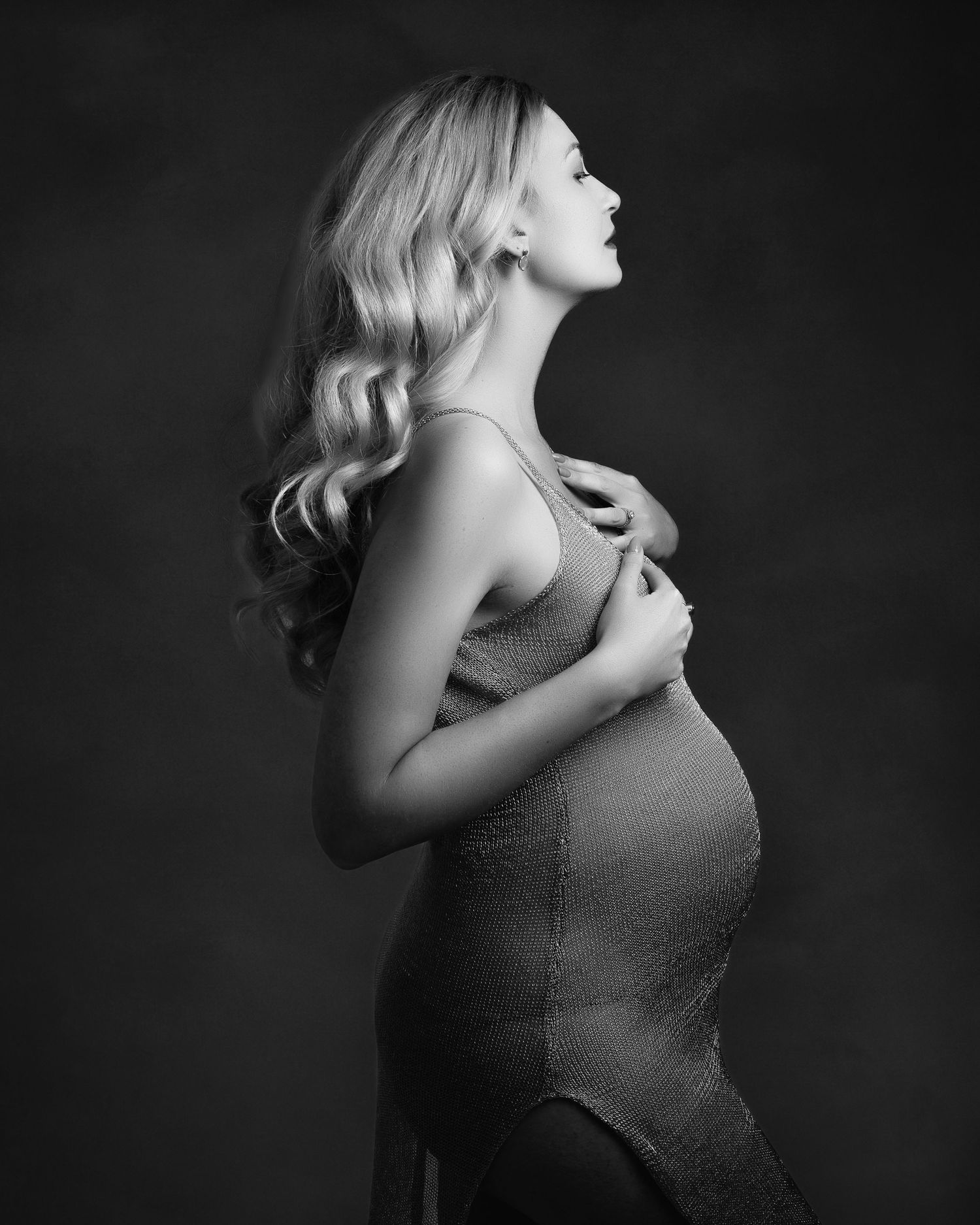 Artistic black and white maternity photo showing profile view with flowing hair.