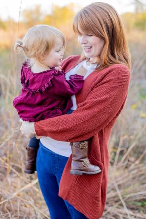 A sweet autumn portrait showing affection between parent and child in a burgundy dress among tall grasses in Springfield, MO.