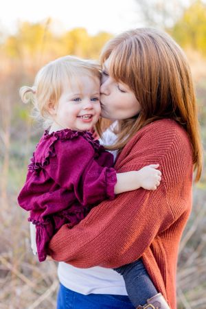 Intimate moment between parent and child wearing matching burgundy outfits in an autumn field in Springfield, MO.