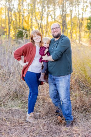 Casual family portrait with toddler against golden autumn trees and natural landscape in Springfield, MO.