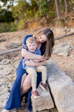 Parent and child share a joyful moment while sitting on rocky terrain outdoors in Springfield, MO.