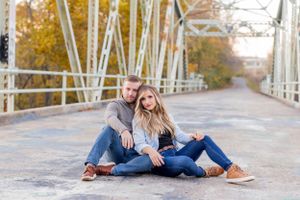 Couple sitting together on metal bridge during autumn photoshoot in Springfield, MO.